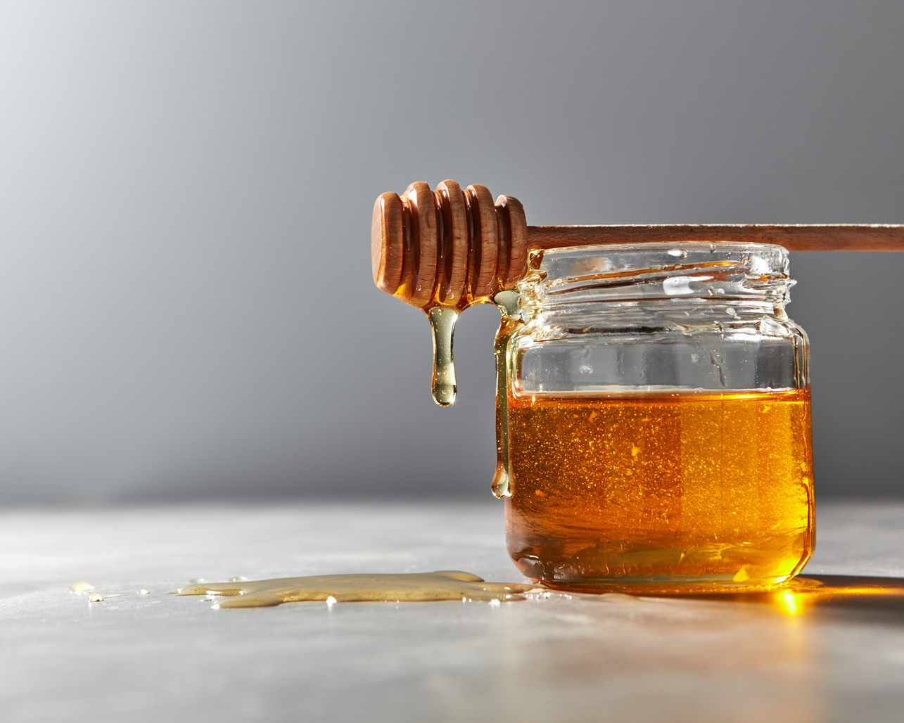 Dripping Organic Natural Fresh Honey from Glass Pot on a Gray Kitchen Table. Rosh Hashanah Jewish New Year Healthy Holiday .